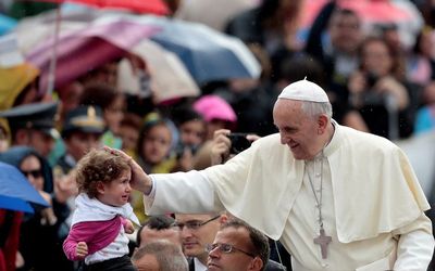Pope Francis blesses a child as he arrives to lead the weekly audience in Saint Peter's Square at the Vatican. Picture: REUTERS