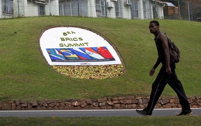 IN TOWN: A man walks past a floral display in Durban announcing the fifth annual Brics Summit. Picture: REUTERS