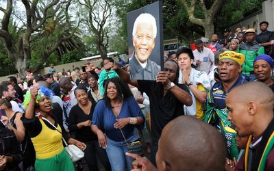 Hundreds of people gathered outside Nelson Mandela's home in Houghton, Johannesburg, on Friday to pay tribute to the late leader. Picture: GCIS