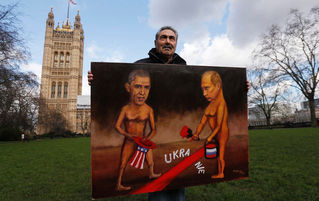 Artist Kaya Mar holds a satirical painting depicting US President Barack Obama and Russian President Vladimir Putin in Ukraine, outside the Houses of Parliament in London on Tuesday. Picture: REUTERS