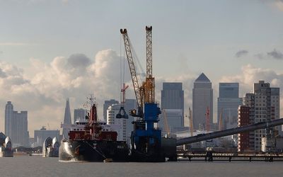 Cranes are used to unload a bulk carrier at the Tate and Lyle sugar refinery in front of London's financial district of Canary Wharf.  Picture: REUTERS