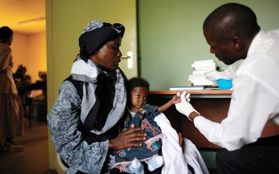 A mother holds her child while she is screened by a clinical worker. Picture: BLOOMBERG