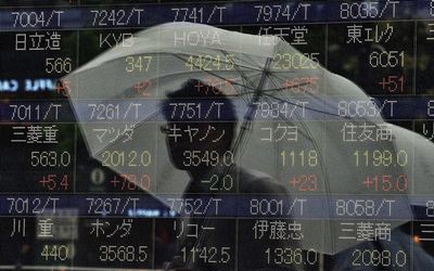 A pedestrian is reflected on a share prices board in Tokyo. Picture: AFP