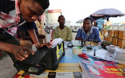 A man enters a customer’s mobile cellphone sim card details on an MTN Group Ltd. registration machine at a roadside kiosk in Lagos last week.   Picture: BLOOMBERG/GEORGE OSODI