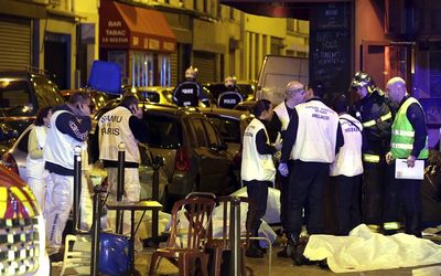 A general view of the scene shows rescue service personnel working near the covered bodies outside a restaurant following a shooting incident in Paris on Friday. Picture: REUTERS