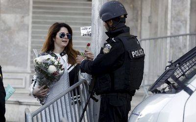 Tunisian woman gives flowers to a policeman in Tunis. The clear lesson from Tunisia remains that supporting civil society efforts can be a cost-effective way of preventing violent conflicts, says the writer. Picture: REUTERS