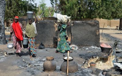 Young girls fleeing from Boko Haram Islamists pass burnt houses in Mairi village in northeast Borno State, Nigeria. Picture:  AFP PHOTO