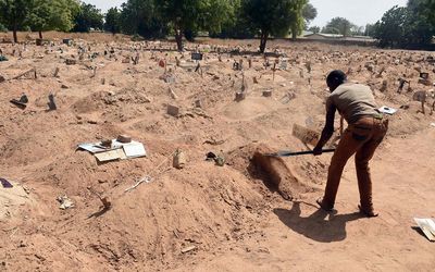 A grave digger heaps sand on graves where victims of Boko Haram Islamists are buried at Gwange Cemetery in Maiduguri, northeast Nigeria, in early February. Picture: AFP PHOTO/PIUS UTOMI EKPEI