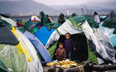Migrant children stand in front of a tent at a makeshift camp on the Greek-Macedonian border on Thursday. German Chancellor Angela Merkel  has staking her political capital on a unilateral initiative to resolve the migrant crisis. Picture:  AFP PHOTO/DIMITAR DILKOFF