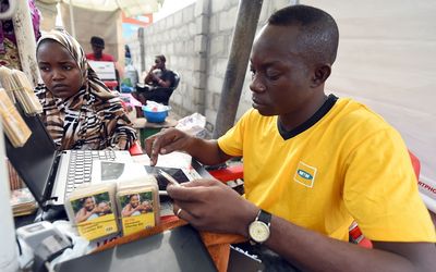 An employee of mobile phone operator MTN tries to register a client with the network in the Obalende district of Lagos on Tuesday. Picture: AFP PHOTO/PIUS UTOMI EKPEI