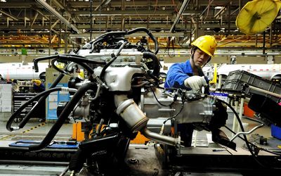 HARD AT WORK: An employee works on an assembly line producing vehicles at a factory in Qingdao, China. Picture: REUTERS