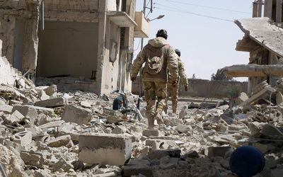 DESTROYED: Syrian troops walk in the streets of the residential neighbourhoods in  the modern town adjacent to the ancient Syrian city of Palmyra. Picture: AFP