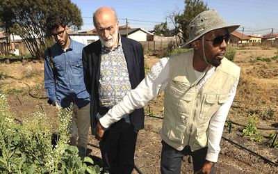Slow Food Italy’s Francesco Anastasi, left, and Slow Food founder Carlo Petrini visit the garden of Soweto smallholder Phila Cele to sample his special brand of chilli. Picture: MALCOLM DRUMMOND