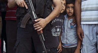 BOYS IN A WAR: Palestinian boys peek from behind a Hamas militant during a parade in Shejaiya on Wednesday. Picture: AFP