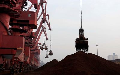 Cranes unload iron ore from a ship at a port in Rizhao, Shandong province, China.  Picture: REUTERS