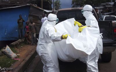 MEDICAL AID: Health workers remove the body of a man believed to have died from the Ebola virus at a street in Monrovia, Liberia, on October 27 2014. Picture: REUTERS