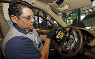 ROCKY ROAD: Technician Edward Bonilla holds a recalled Takata air bag inflator after he removed it from a Honda Pilo. The yellow circular device is the airbag inflator. The head of Japan’s Takata’s head Corpsaid an internal probe into its potentially deadlyair bag inflators was not progressing well, but vowed to stay at the helm until trust in the safety of its products was restored. Picture: REUTERS